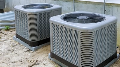 Two outdoor air conditioning units installed on a concrete base, highlighting HVAC systems essential for effective cooling and heat transfer in residential settings.