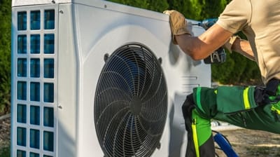 Technician servicing a heat pump unit outdoors, emphasizing HVAC maintenance and repair in Hemet, CA.