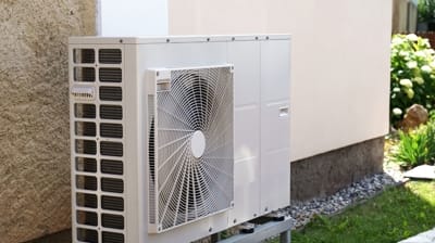 Outdoor heat pump unit installed next to a residential building, showcasing energy-efficient heating and cooling technology in Hemet, CA.