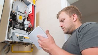 HVAC technician inspecting heating system with maintenance tablet, ensuring efficiency and performance for optimal home heating.